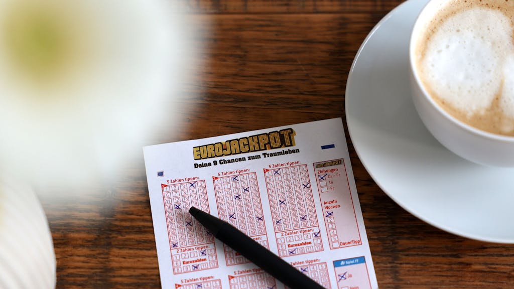 Eurojackpot Spielschein liegt auf dem Tisch neben einer Tasse Kaffee.