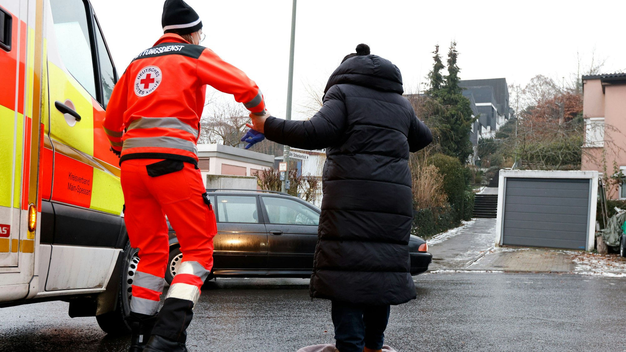 Der Rettungsdienst hilft einer Dame bei Glätte über die Straße.