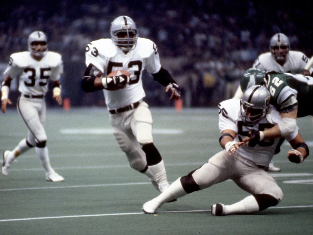 Raiders Linebacker Rod Martin hat eine Interception gefangen und läuft mit dem Ball übers Feld.