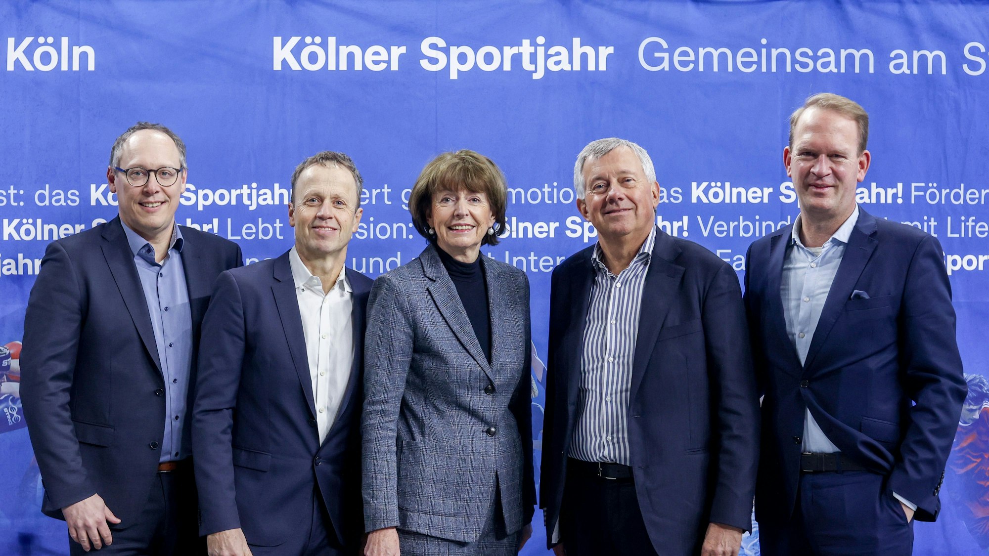 Vertreter aus dem Sport, der Geschäftsführer der Lanxess-Arena Stefan Löcher und Oberbürgermeisterin Reker stehen vor einem Werbeplakat des Kölner Sportjahres.