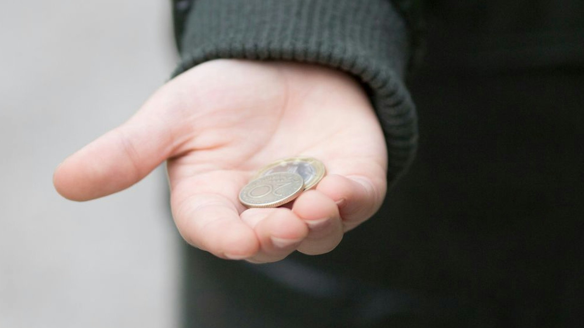 Ein Kind hält ein paar Münzen in der Hand.