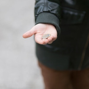 Ein Kind hält ein paar Münzen in der Hand.