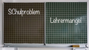 Auf einer Schultafel stehen rechts der Begriff „Lehrermangel“ und links „Schulproblem“, beides in Kreideschrift.