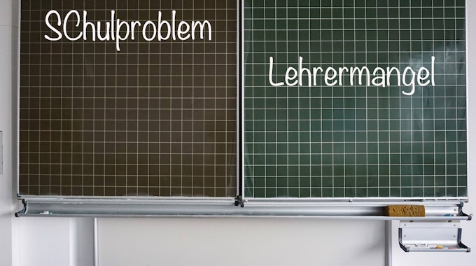 Auf einer Schultafel stehen rechts der Begriff „Lehrermangel“ und links „Schulproblem“, beides in Kreideschrift.&nbsp;