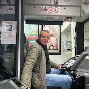 Busfahrer Nico Neumann sitzt am Steuer eines Linienbusses.