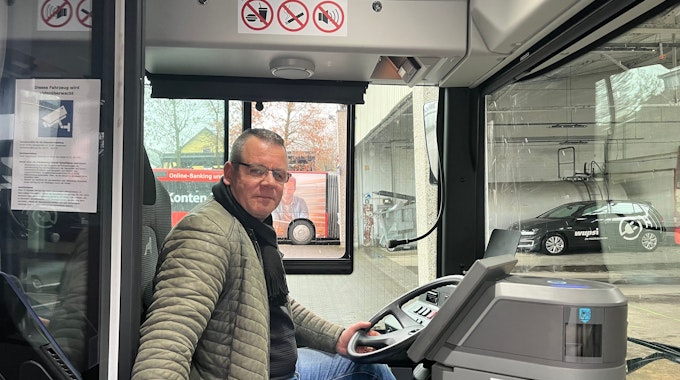 Busfahrer Nico Neumann sitzt am Steuer eines Linienbusses.