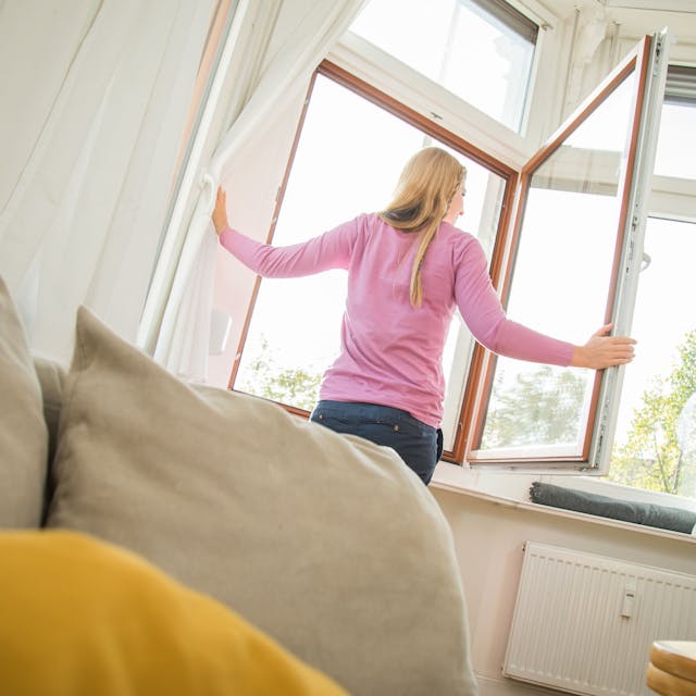 Eine Frau öffnet das Fenster, um ihre Wohnung zu lüften.