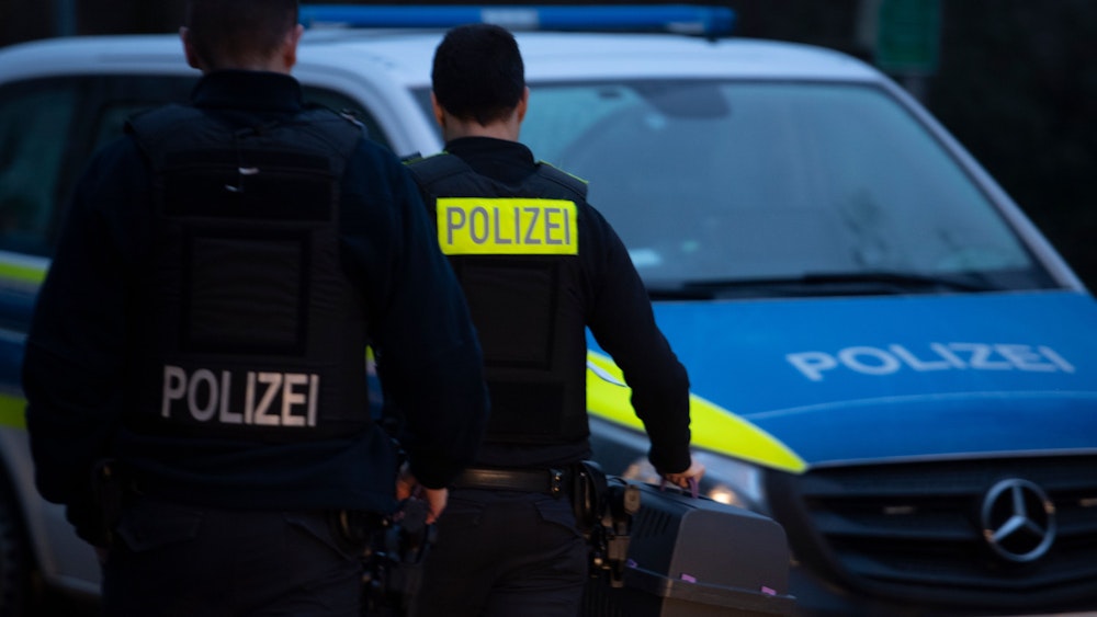 Polizeibeamte gehen mit einer Hundetransportbox in Lichtenberg zu einem Fahrzeug.