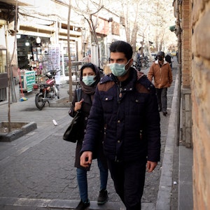 Ein iranisches Paar geht im Stadtteil Shapour im Süden Teherans die Straße entlang.