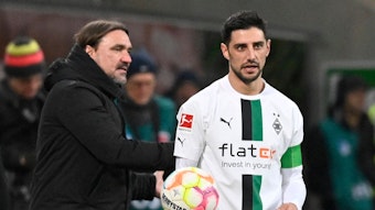 Daniel Farke (l.), Trainer von Borussia Mönchengladbach, gibt Kapitän Lars Stindl im Bundesliga-Spiel am 28. Januar 2023 bei der TSG Hoffenheim den Ball und spricht mit dem Gladbach-Spieler, der das weiße Heimtrikot von Borussia trägt.