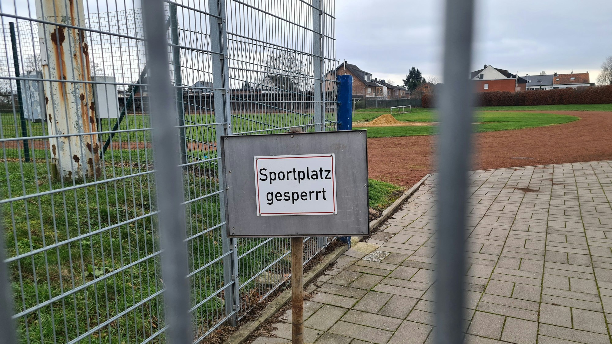 Auf dem Foto ist der Rasenplatz des Jahnstadions in Bergheim zu sehen. Auf einem Schild ist zu lesen "Sportplatz gesperrt".