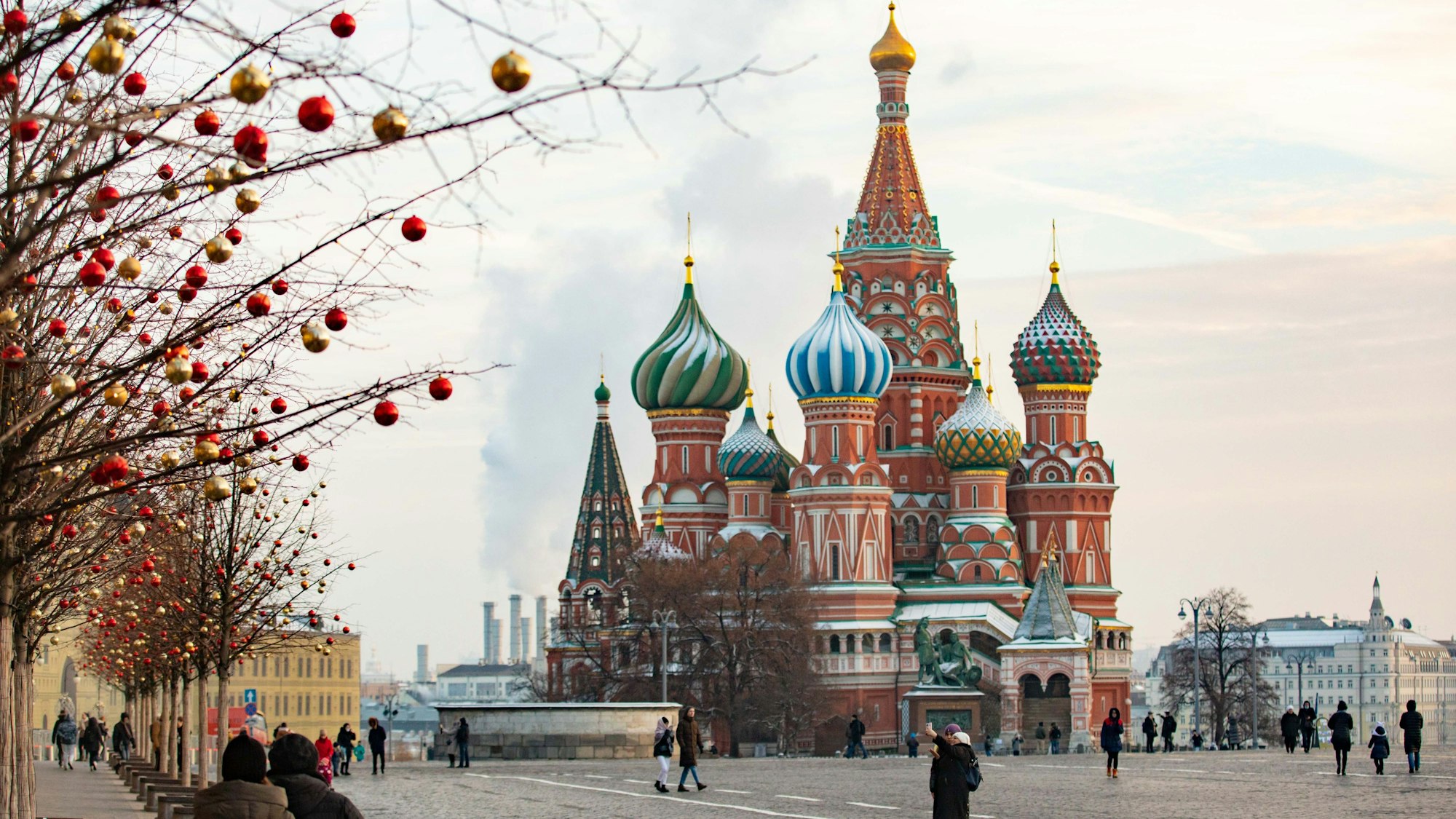 Passanten gehen über den Roten Platz vor der Basilius-Kathedrale im russischen Moskau.