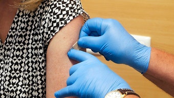 Nach einer Corona-Impfung klebt ein Arzt ein Pflaster auf den Arm einer Frau.