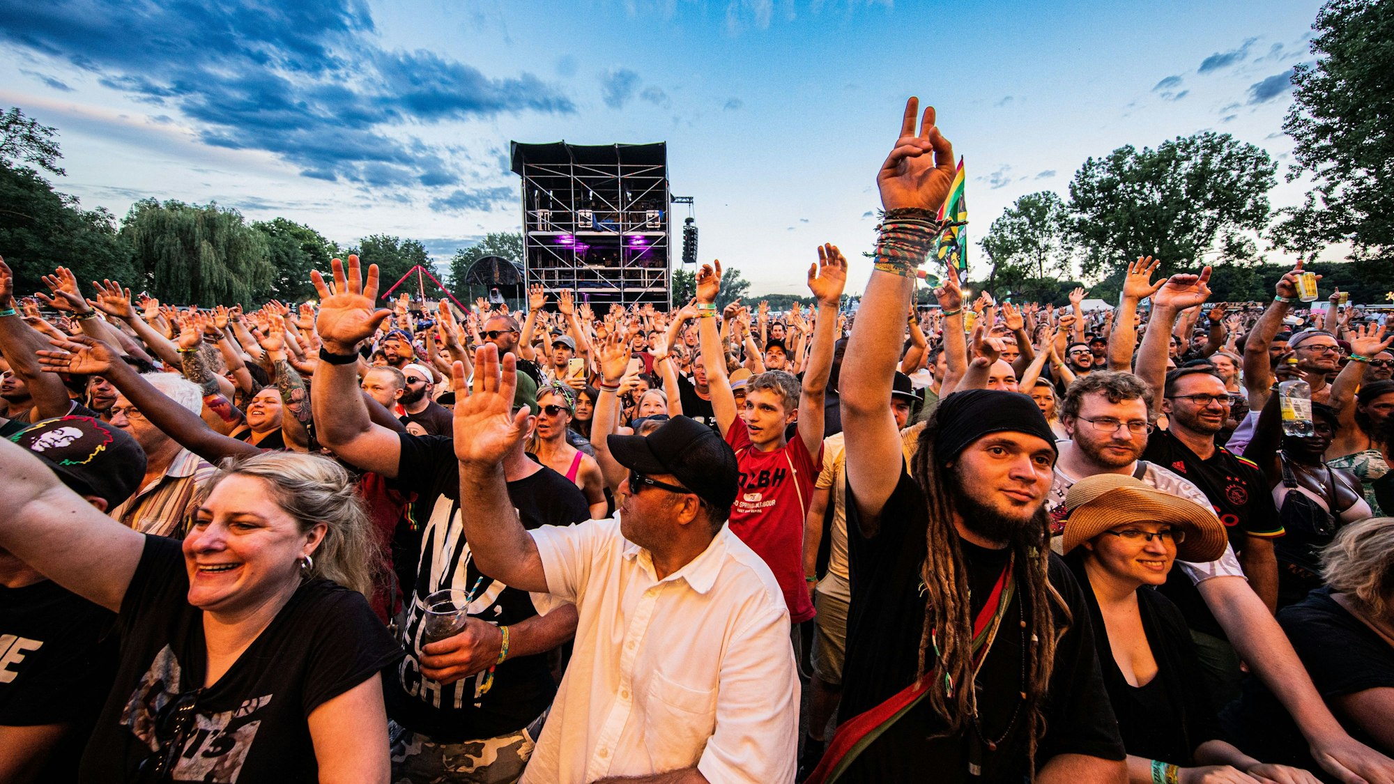 Hunderte Menschen heben die Arme im Publikum des Summerjam-Festivals am Fühlinger See.