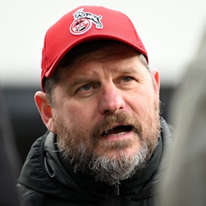 Steffen Baumgart, der Trainer des 1. FC Köln, unterhält sich am Geißbockheim mit Journalisten. Er trägt eine rote FC-Kappe und eine dicke Winterjacke.