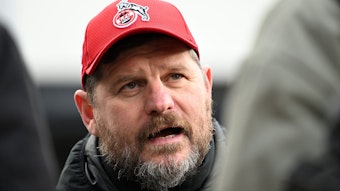 Steffen Baumgart, der Trainer des 1. FC Köln, unterhält sich am Geißbockheim mit Journalisten. Er trägt eine rote FC-Kappe und eine dicke Winterjacke.