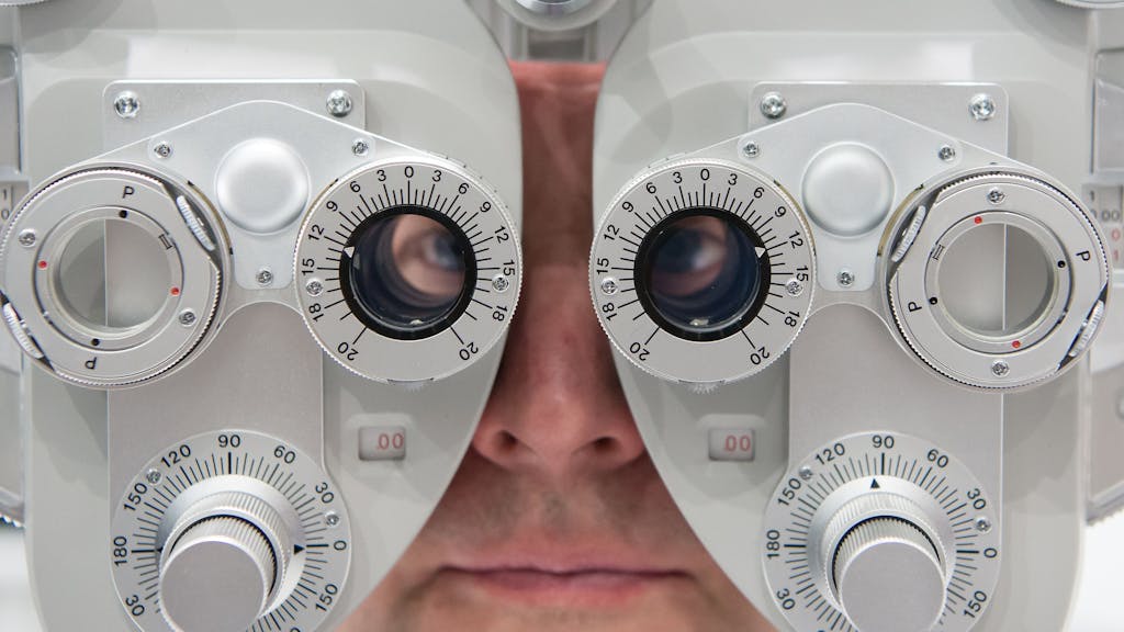 Ein Mann, hier im Januar 2016 in München, sitzt auf der Optik- und Brillenmesse Opti hinter einem Phoropter.