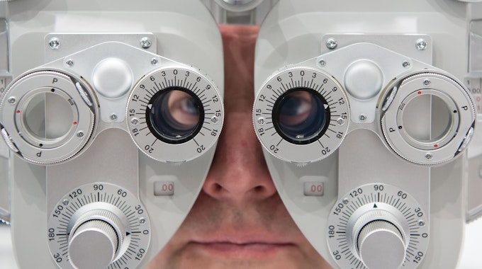Ein Mann, hier im Januar 2016 in München, sitzt auf der Optik- und Brillenmesse Opti hinter einem Phoropter.