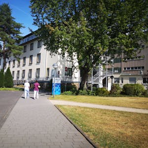 Das Foto zeigt das Krankenhaus Wesseling von außen. Zwei Frauen gehen Richtung Eingang.