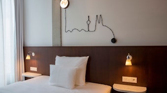 Ein Hotelzimmer mit einer Lichtleiste in Form des Köln-Panoramas über dem Bett