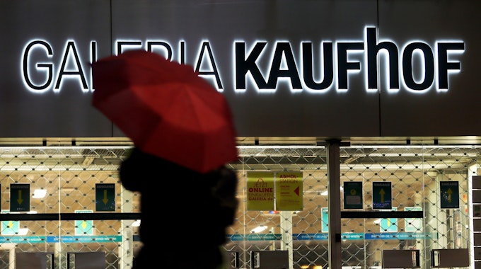 ARCHIV - 27.01.2021, Nordrhein-Westfalen, Köln: Eine Frau geht mit Regenschirm an einer geschlossenen Kaufhof Filiale vorbei.&nbsp;