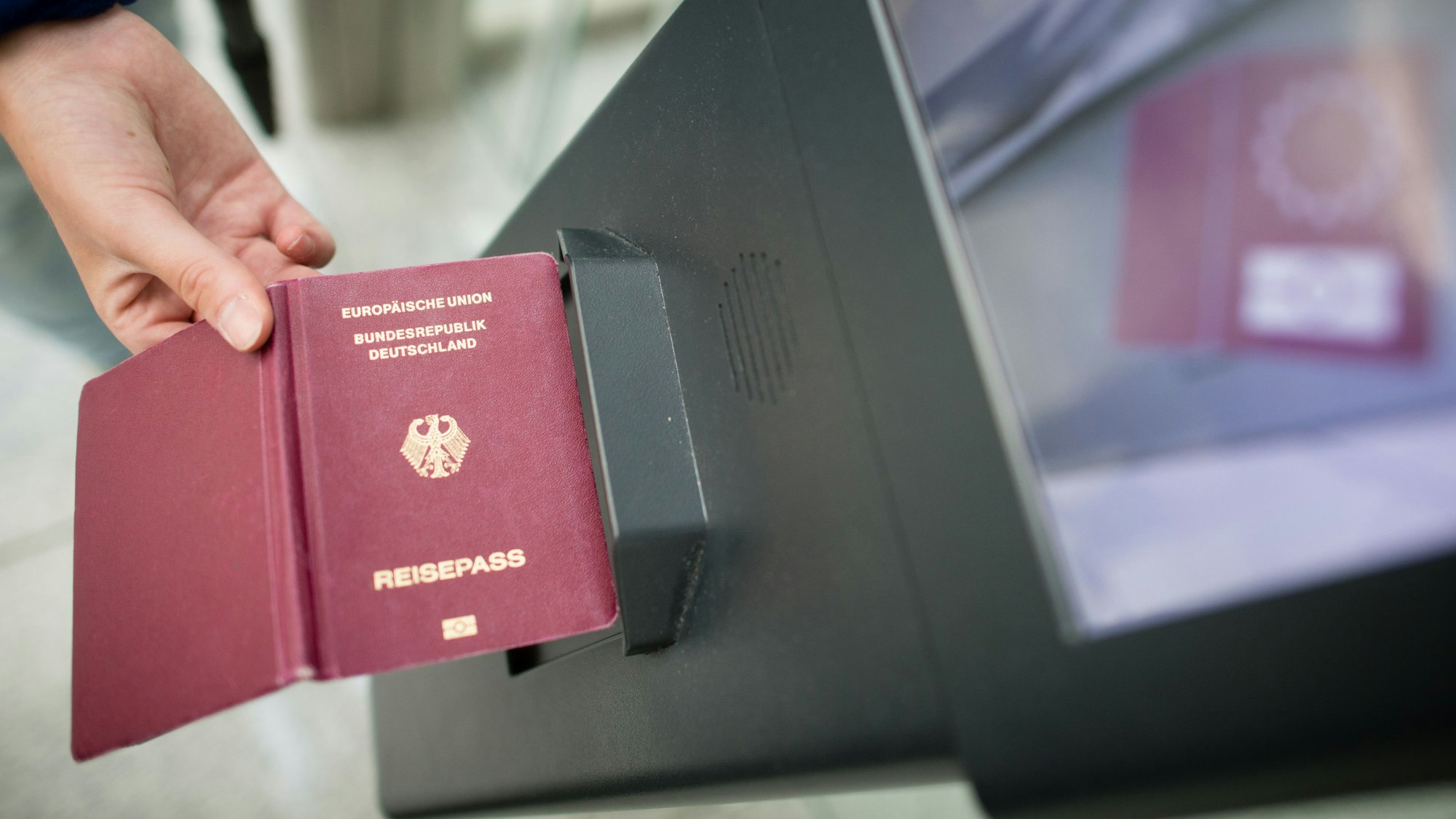 Eine Frau hält einen Reisepass an das Lesegerät eines EasyPass-Systems zur teilautomatisierten Grenzkontrolle am Flughafen in München (Bayern).