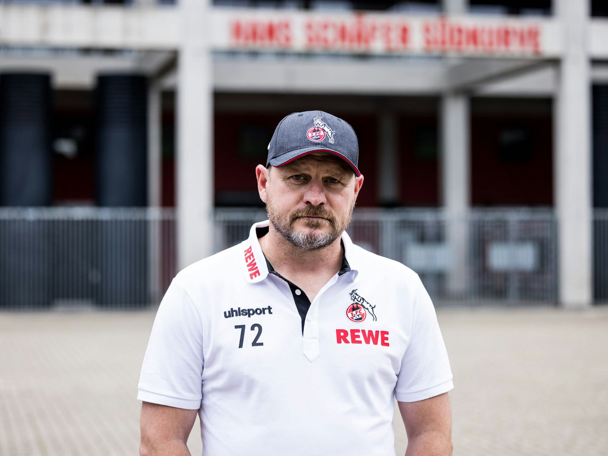 Steffen Baumgart steht vor dem Rheinenergie-Stadion und blickt in die Kamera.
