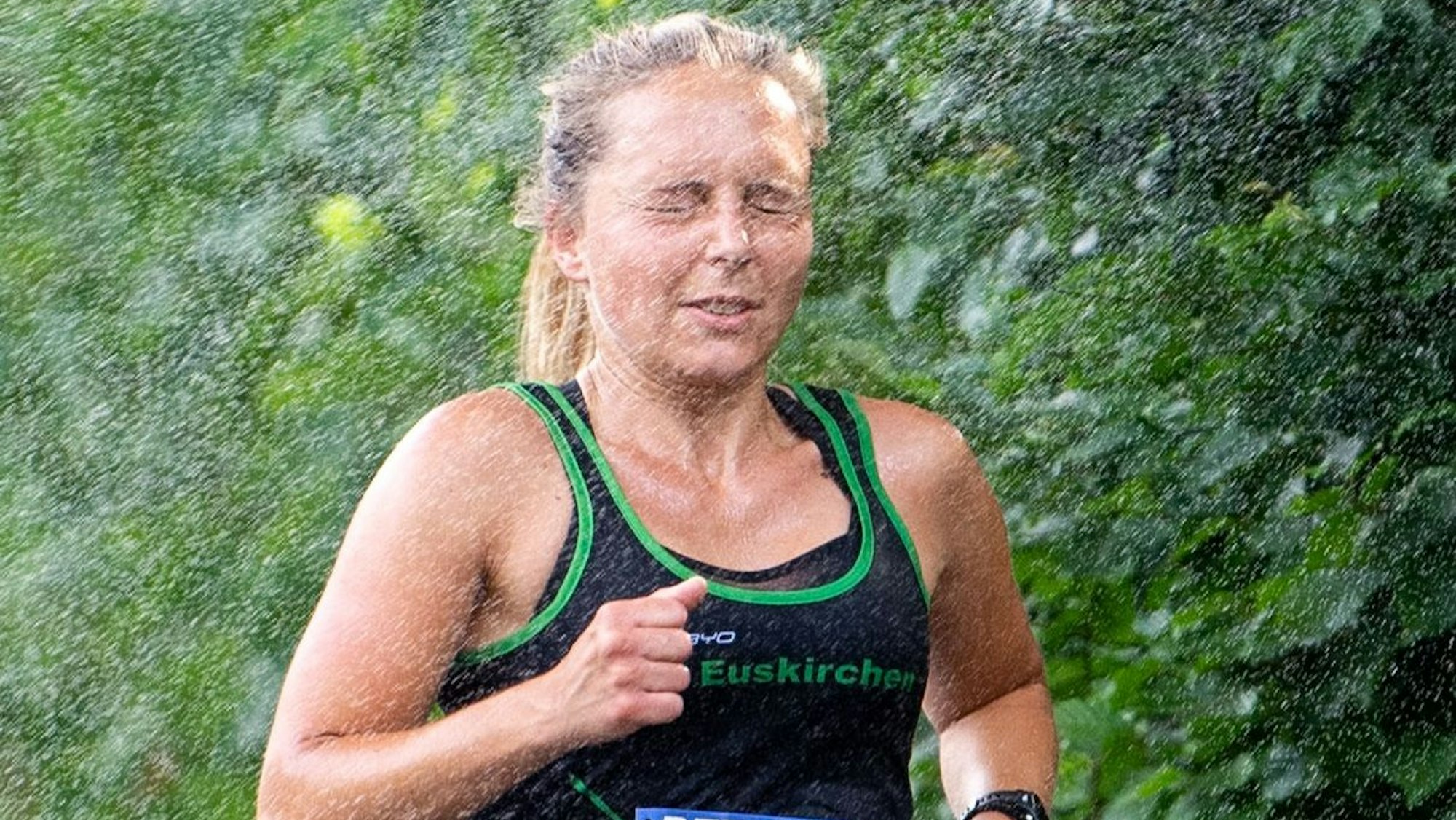 Nora Schmitz rennt beim Eifel-Cup-Lauf in Kreuzweingarten durch den Brausestrahl einer bereitgestellten Dusche.