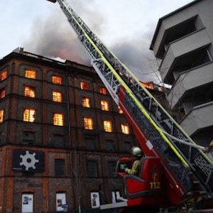 03.02.2023, Baden-Württemberg, Mannheim: Einsatzkräfte der Feuerwehr versuchen von einer Drehleiter aus einen Brand in einem Gewerbegebäude zu löschen.