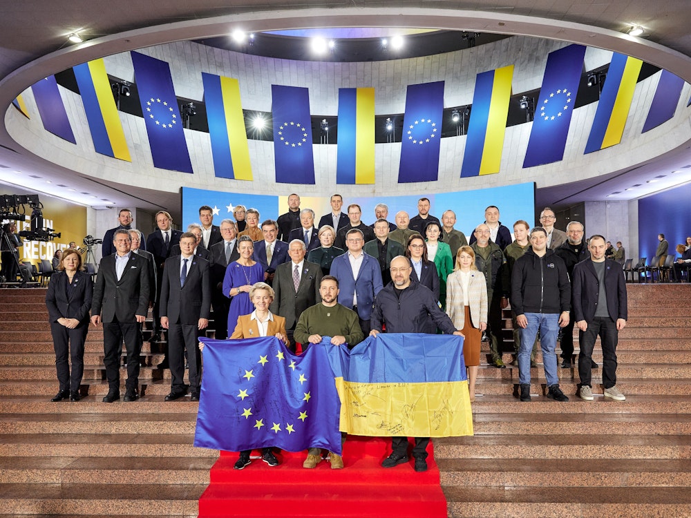 Wolodymyr Selenskyj (vorne M), Präsident der Ukraine, Ursula von der Leyen (vorne l), Präsidentin der EU-Kommission, und Denys Schmyhal (vorne r), Ministerpräsident der Ukraine, halten eine europäische und eine ukrainische Fahne während eines Gruppenfotos nach dem EU-Ukraine-Gipfel. Erstmals seit der Beginn der russischen Invasion in die Ukraine reisen gleich 16 Vertreter der EU-Kommission in die Hauptstadt Kyjiw Die Reise ist vor allem ein Zeichen dafür, dass die EU weiter an der Seite des angegriffenen Landes steht. +++ dpa-Bildfunk +++