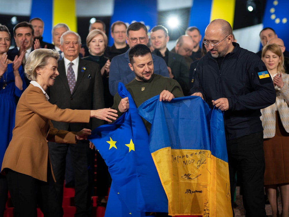 Wolodymyr Selenskyj (M), Präsident der Ukraine, und Ursula von der Leyen (l), Präsidentin der EU-Kommission, und Denys Schmyhal (r), Ministerpräsident der Ukraine, halten eine europäische und eine ukrainische Fahne während des EU-Ukraine-Gipfels. Erstmals seit der Beginn der russischen Invasion in die Ukraine reisen gleich 16 Vertreter der EU-Kommission in die Hauptstadt Kyjiw. Die Reise ist vor allem ein Zeichen dafür, dass die EU weiter an der Seite des angegriffenen Landes steht. +++ dpa-Bildfunk +++