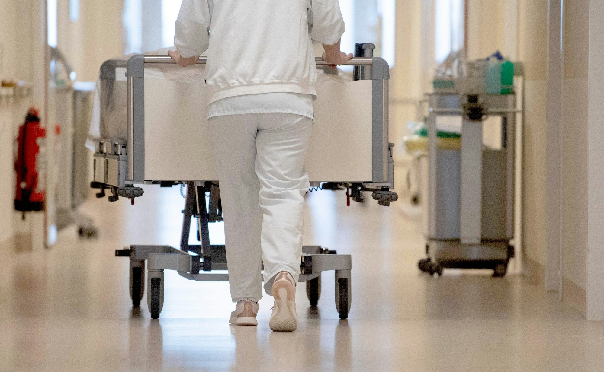 ARCHIV - 20.01.2020, Baden-Württemberg, ---: Eine Krankenpflegerin schiebt ein Krankenbett durch einen Flur.