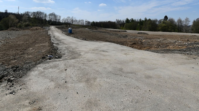 Ein braches Feld mit einem nicht-befestigten Weg und einem Dixxi-Klo
