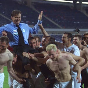 Die Spieler des 1. FC Köln heben ihren Trainer Ewald Lienen hoch.