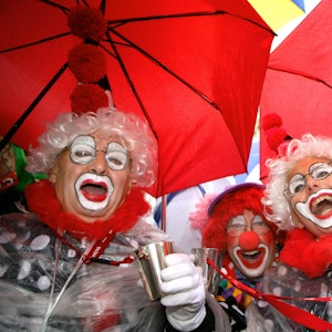 Jecken feiern auf dem Heumarkt in Köln. Sie haben rote Regenschirme über sich aufgespannt. Das Foto ist ein Archivbild von 2006.