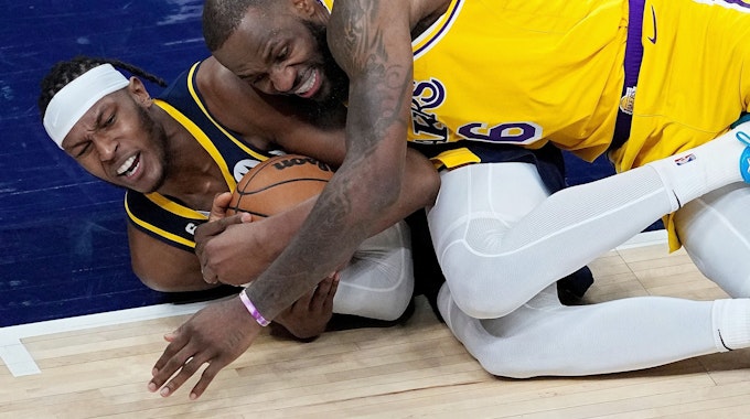 Myles Turner von den Indiana Pacers und LeBron James von den Los Angeles Lakers kämpfen am Boden liegend um den Ball.