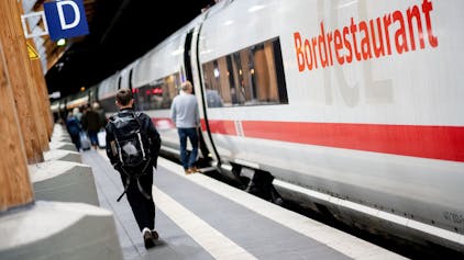 Fahrgäste gehen am frühen Morgen mit ihrem Gepäck über einen Bahnsteig am Hauptbahnhof, um in einen ICE der Deutschen Bahn (DB) einzusteigen.