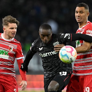 Moussa Diaby von Bayer 04 Leverkusen im Zweikampf mit zwei Spielern vom FC Augsburg.