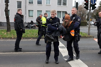 Polizeibeamte tragen einen Aktivisten von der Straße.