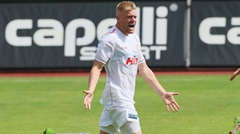 Fortuna-Stürmer Lars Lokotosch steht im Trikot auf einem Fußballplatz und jubelt.