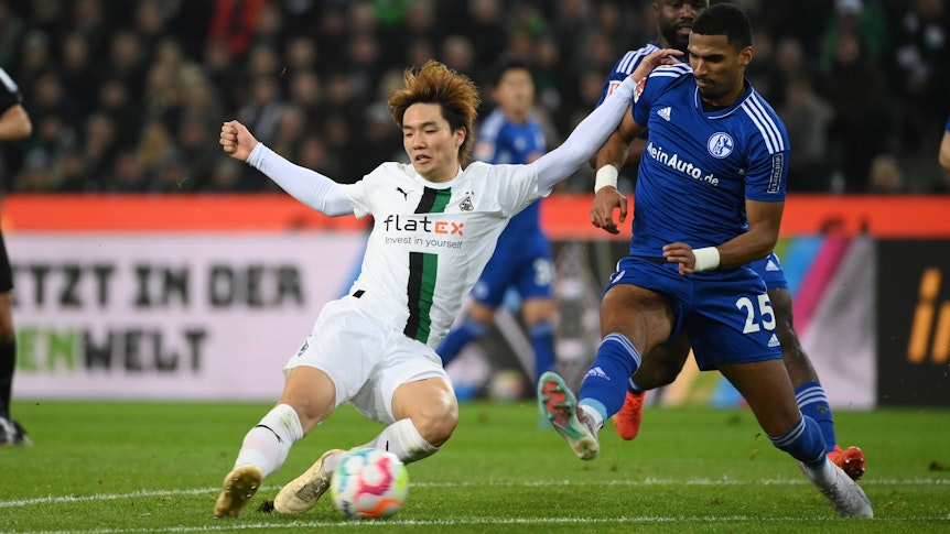 Ko Itakura (l.) von Borussia Mönchengladbach grätscht am 4. Februar 2023 in den Ball und will sich im Duell mit Moritz Jenz von Schalke 04 durchsetzen.
