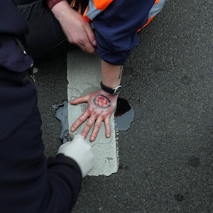 Köln: Polizisten lösen die festgeklebte Hand eines Aktivisten der Umweltgruppe „Letzte Generation“ von der Fahrbahn.