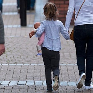 A young girl holds a doll as she is walking hand in hand with a woman in Rotherham, Yorkshire, Britain, 27 August 2014.