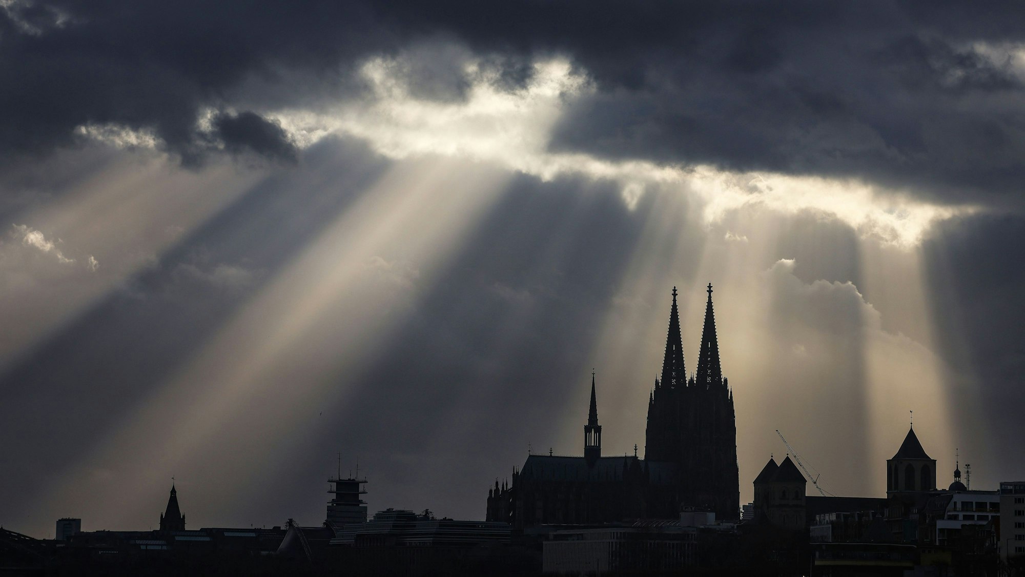 Köln: Sonnenstrahlen scheinen hinter dem Dom aus Wolken.