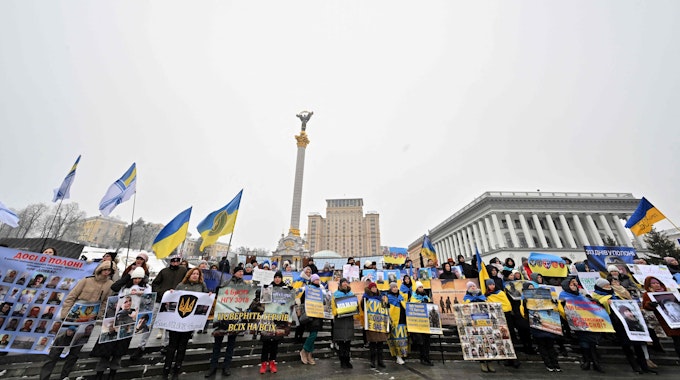 Angehörige von ukrainischen Kriegsgefangenen halten Poster und Portraits in Kiew.