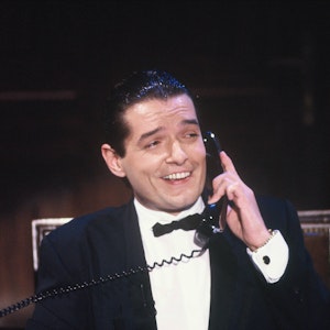Der Sänger Falco bei einem TV-Auftritt in der Show „Wir gratulieren“ am 6.10.1985. Falco hält einen Telefonhörer und lacht.