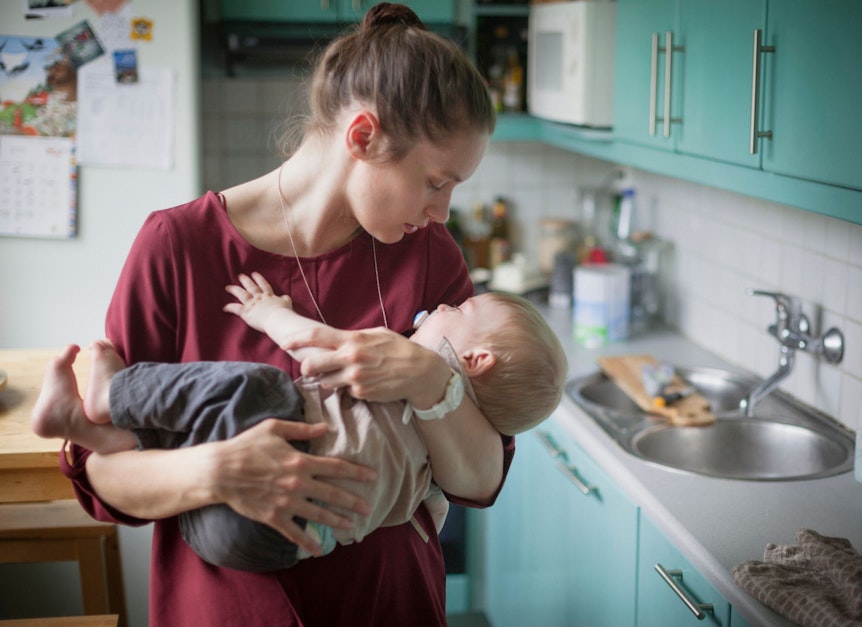 Eine Frau hält ein Baby auf dem Arm in Richtung Körper positioniert, um es zum einschlafen zu bringen.