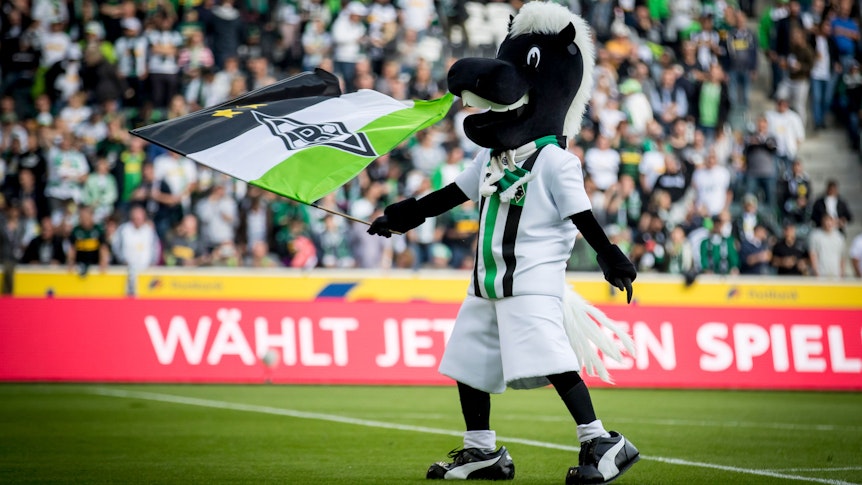 Das Maskottchen von Borussia Mönchengladbach, Jünter, schwenkt auf dem Rasen Borussia-Park seine Fahne.