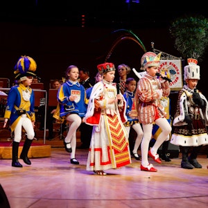 Das Kinderdreigestirn steht auf der Bühne der Kölner Philharmonie.