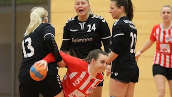 Euskirchens Spielerin Hannah Arends geht zu Boden, eine Hand noch am Ball, ein Arm wird von einer Gegenspielerin festgehalten.